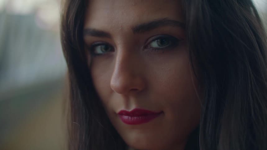 Woman with makeup and brown hair faces the camera with eye contact