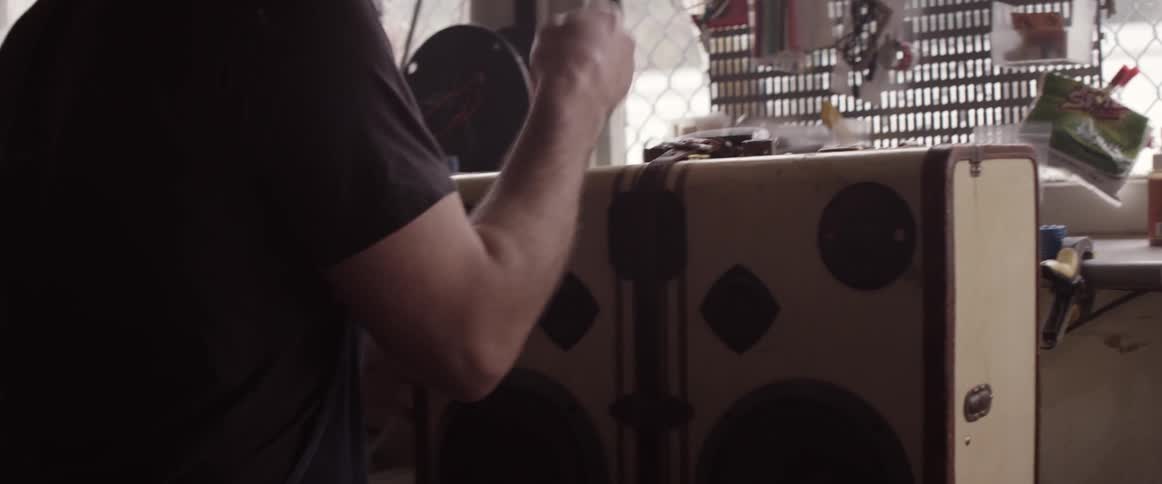 A man carries a briefcase and places it on a workshop  bench