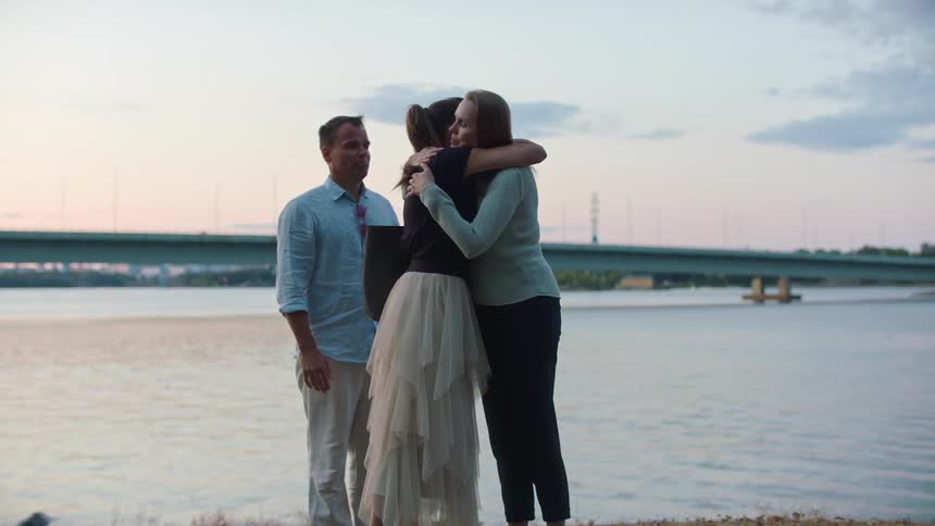 A woman hugs her friends and waves goodbye