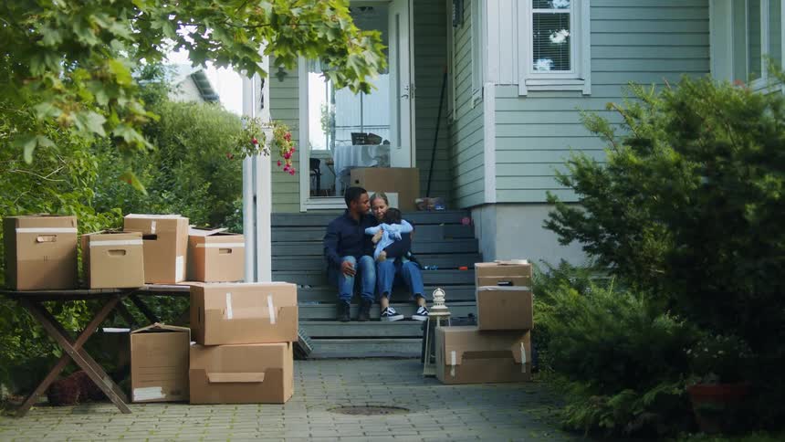 Family relax sitting on the stairs in the porch at home in front of cardboard boxes
