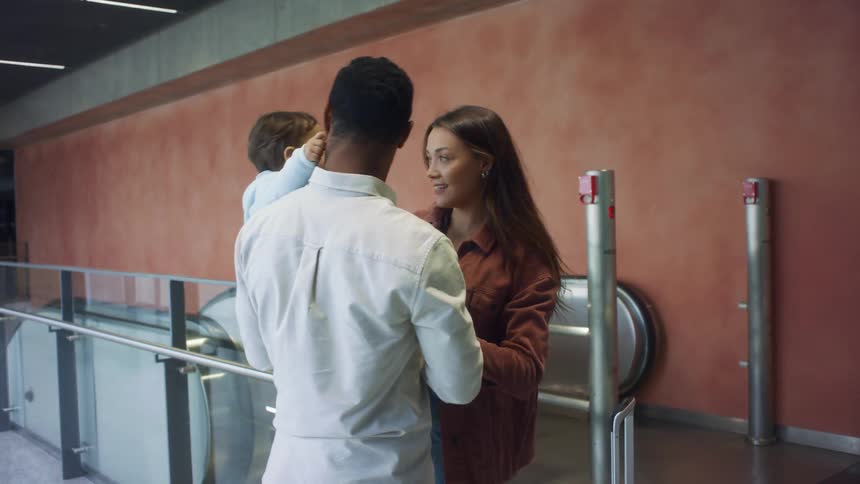 A woman is greeting as she comes off the escalator