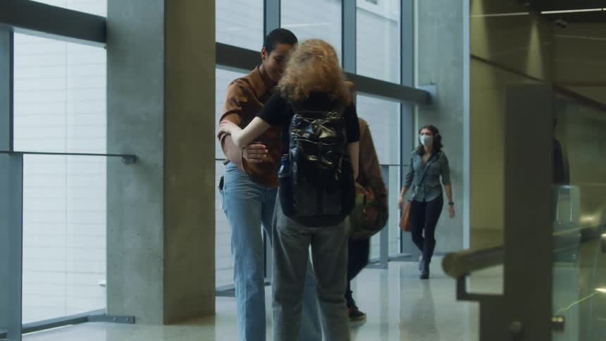 Two women embrace at an aiprort and then they start to walk away