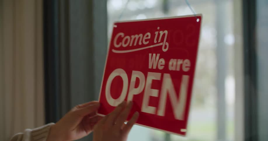 Store staff flips open sign to show the closed side to the outside