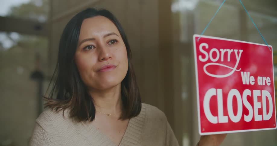 A woman looks outside as she changes the sign to closed