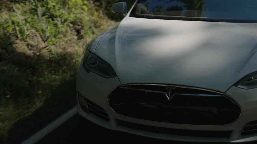 White mid size car rolling along a country road