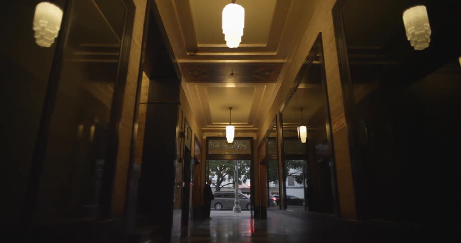 Vehicles on a street drive past the entry way of a building