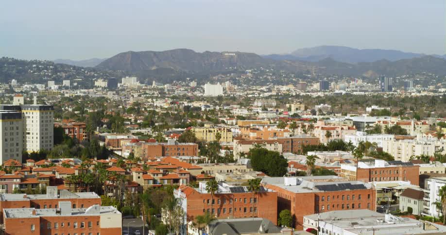 Cars travel on neighborhood streets with mountains and hills on the horizon