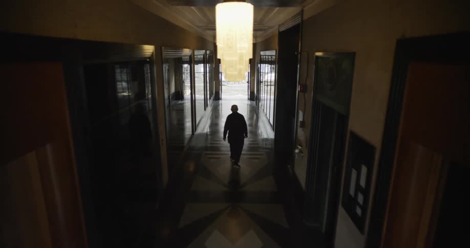 A man is walking down a long corridor hallway