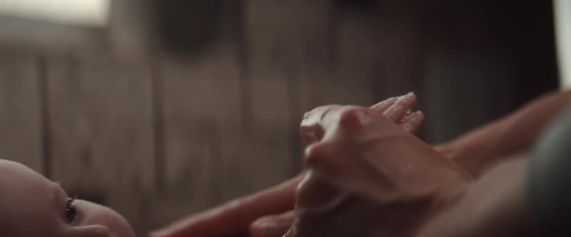 A woman applies soap to her babys arm and chest during a bath