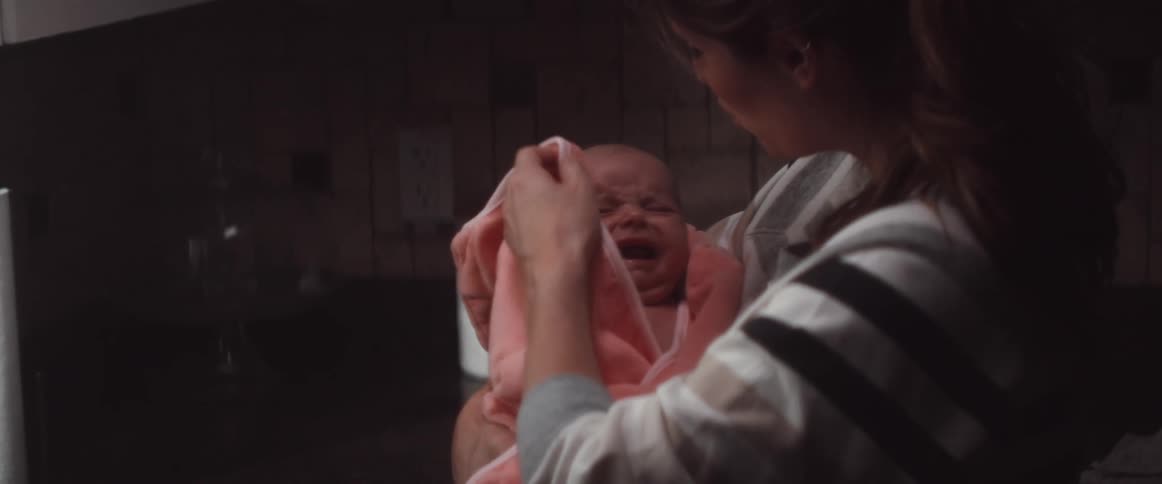 A woman tries to comfort her baby after a bath
