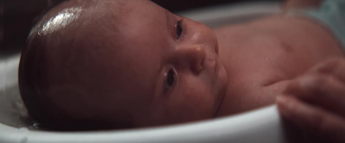 Woman gives baby bath in tub