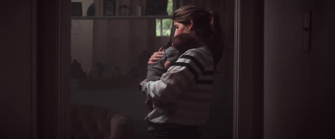 A woman holds her newborn baby and rubs his back as she rocks him