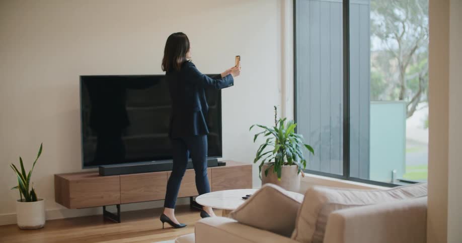 A woman is using her phone to take video of a living room