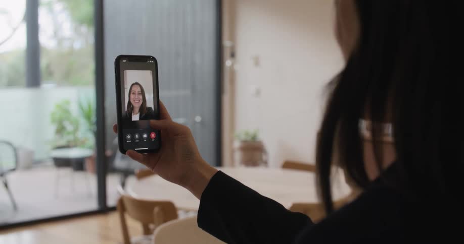 A woman holds her cell phone up as she video chats with a man
