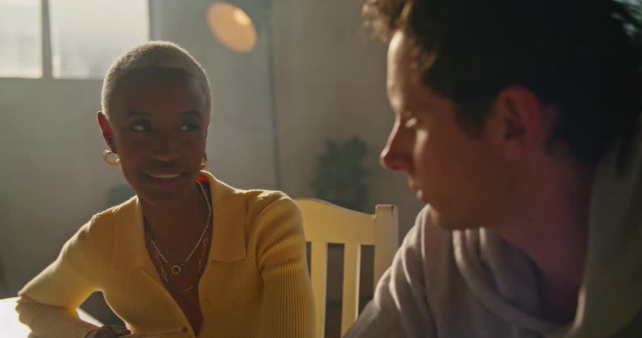 A man and a woman sit next to one another and talk in a room