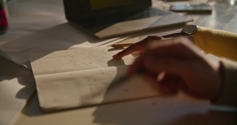 Two people are pointing at things in a notebook