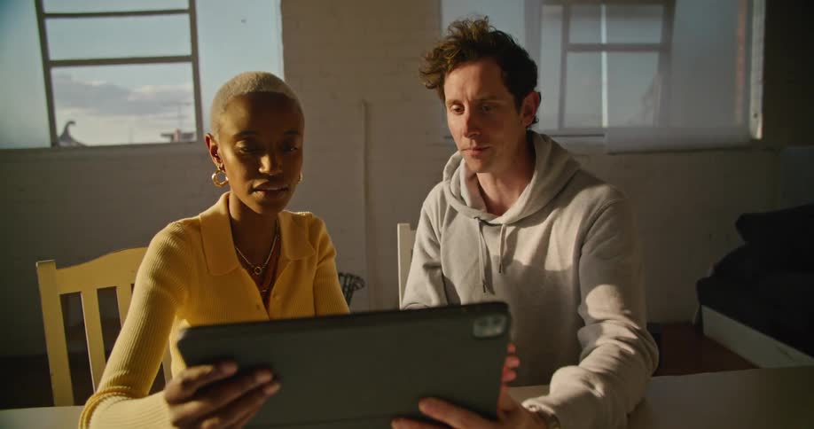 Coworkers talk and look at a tablet together