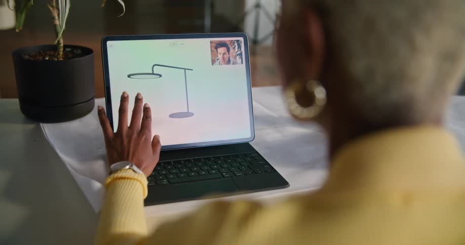 A woman checks a diagram as she is talking with a coworker on the laptop