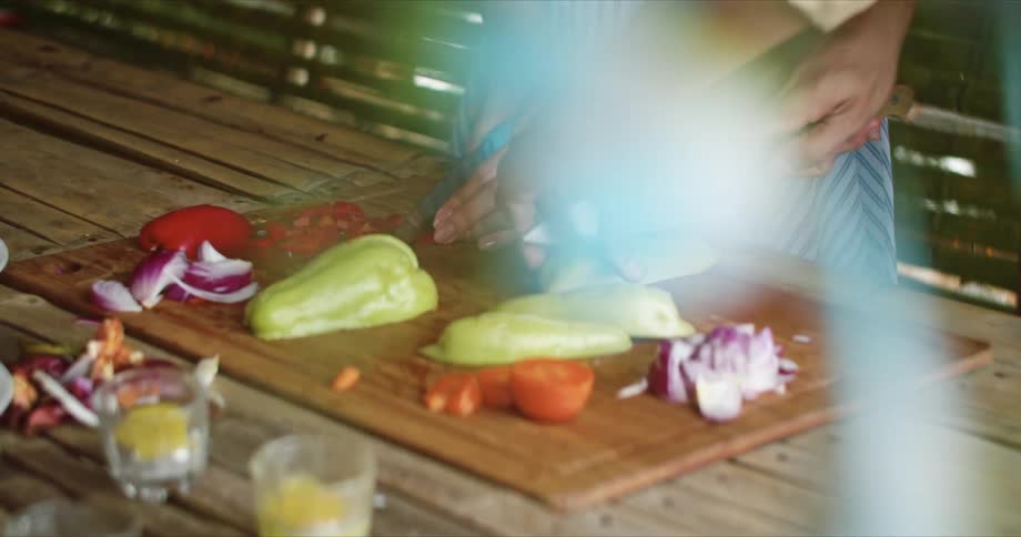 Two women stand next to each other while cutting vegetables on a cutting board