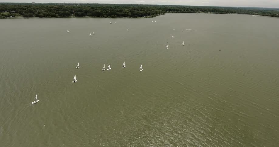 Many sailboats are spread out over a body of water