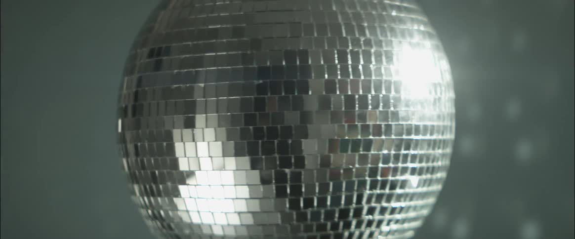 Silver globe spinning and reflecting light in a discotheque