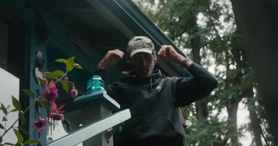 A man stands up outside putting on his hat