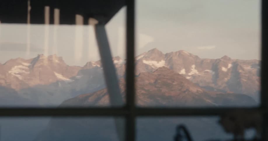Snow covered peaks of a mountain range seen from a window