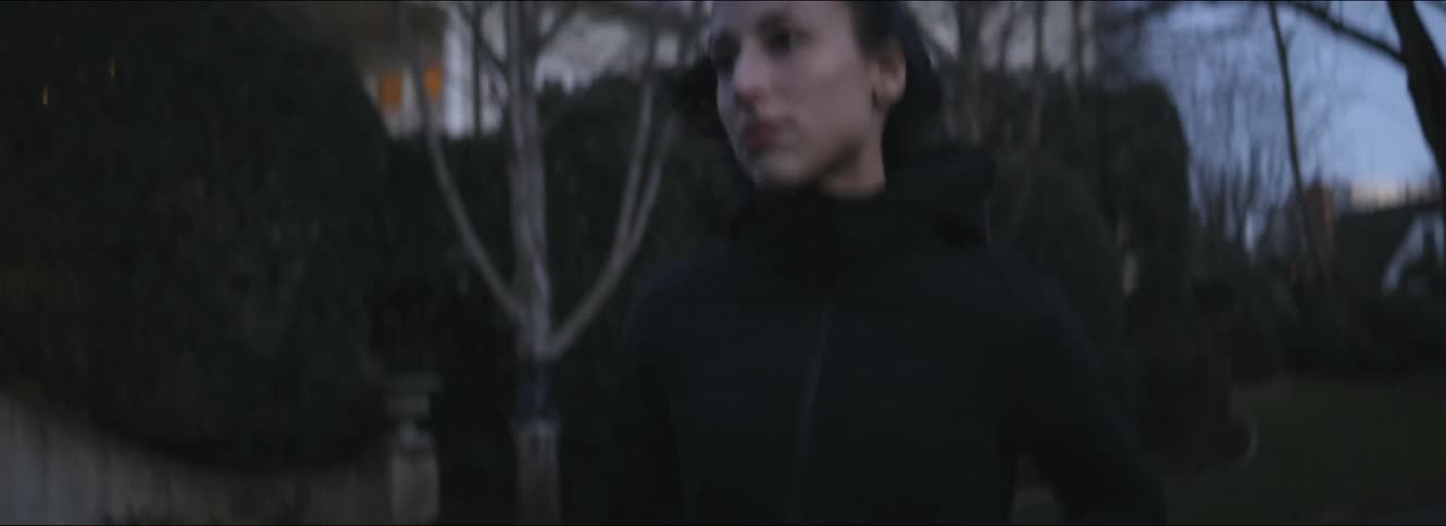 Woman jogs along streets past houses with porch lights on
