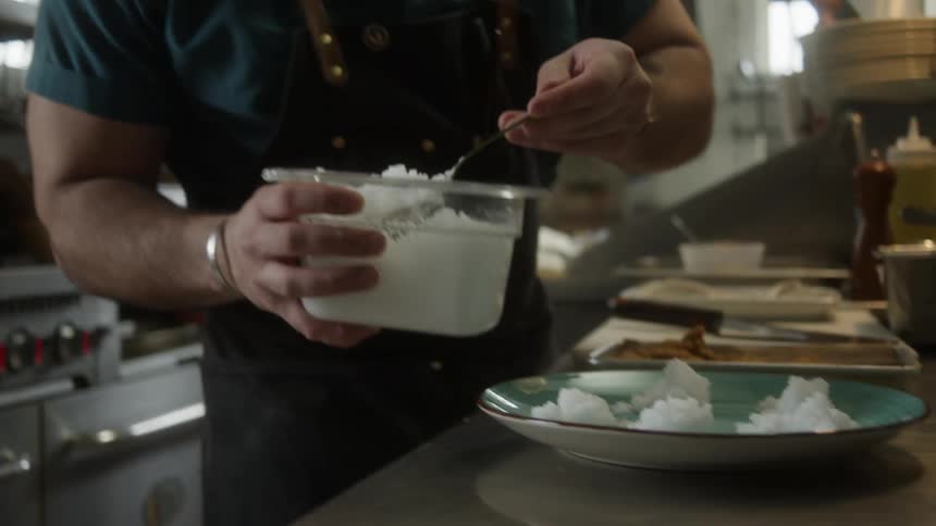 A chef is serving rice on a plate