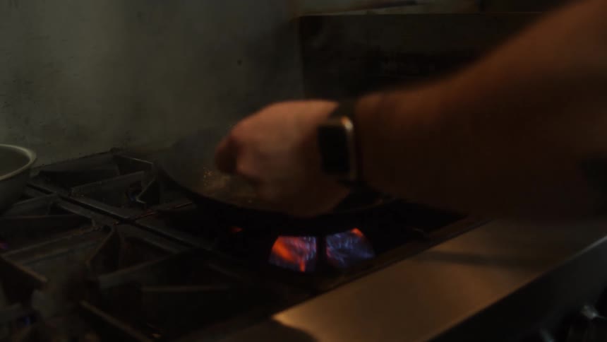 A man cooking a steak in a pan