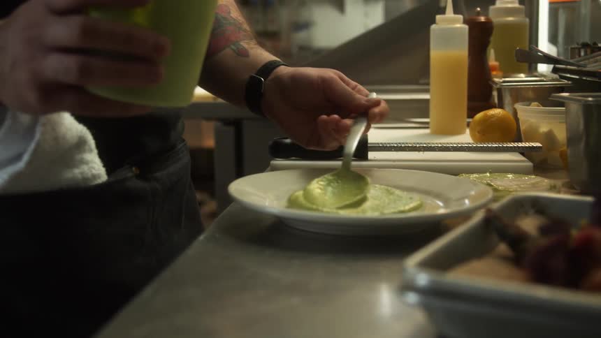 A chef is putting sauce on a plate