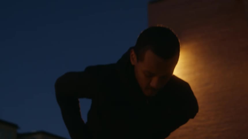 A man stretching with buildings the sky and clouds in the background