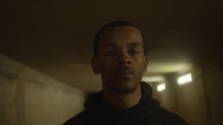 A man in a tunnel with a wall and lights in the background