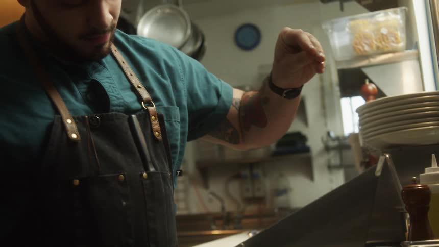 A man sprinkling seasoning on a steak