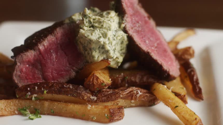 Medium rare steak with french fries on plate in the restaurant