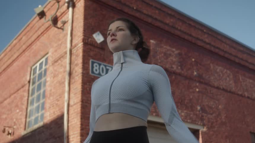 A young woman jumps rope outside a brick building