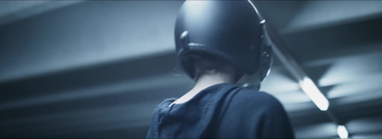 A female driver stands in a parking garage wearing a helmet with visor