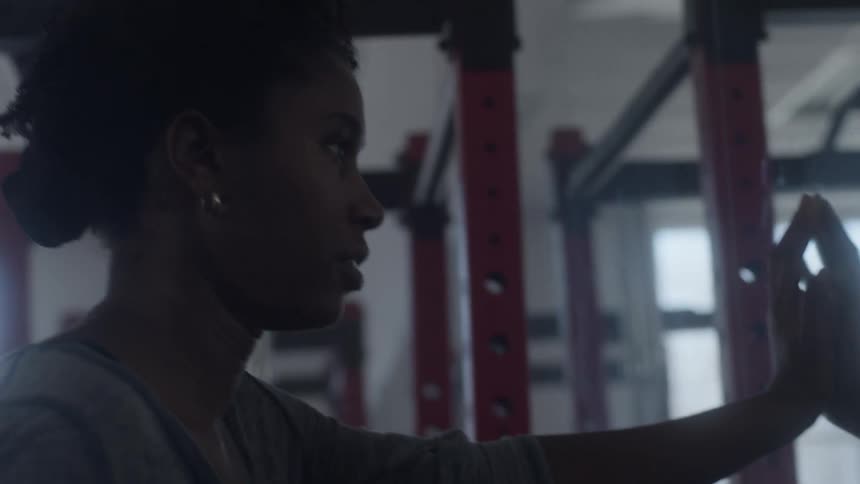 Woman with curly hair earrings and shirt looks in a mirror in the gym