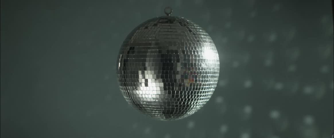 A disco ball slowly spins while hanging from the ceiling