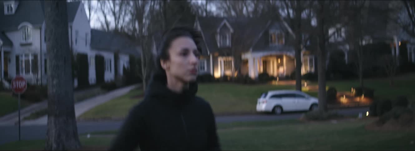 A woman jogging alone on a residential street at dusk