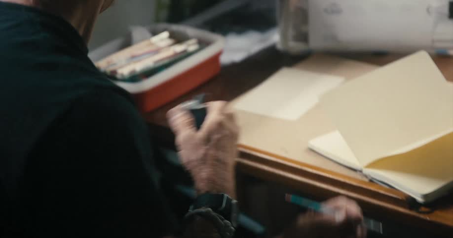 A man sharpens his pencil at his desk