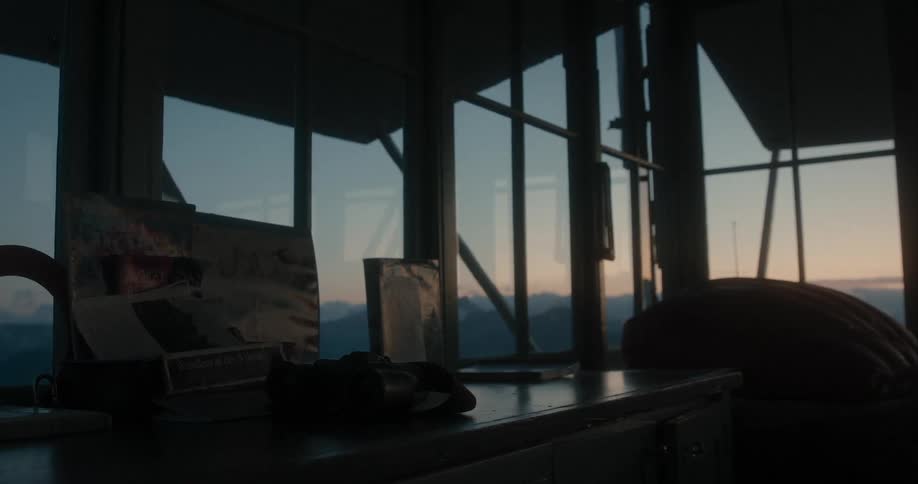 A desk inside a building with walls of windows with hills in the distance