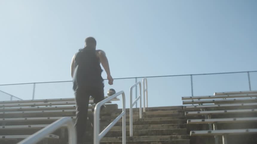 A man is running up steps of some bleachers really fast