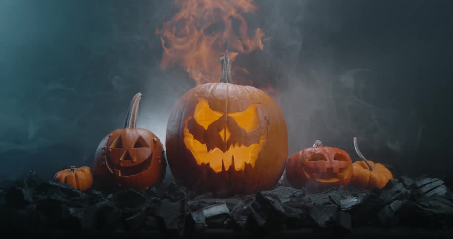 Carved pumpkins are lined up in a display with smoke rising from the middle one