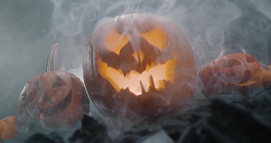 Three pumpkin faces surrounded by smoke