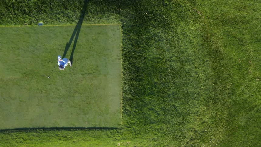 A view of a person hitting a golf ball on a tee