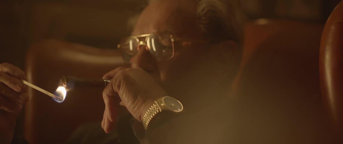 A man lights a large cigar from a match