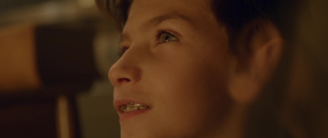 A boy wearing braces looks up smiling