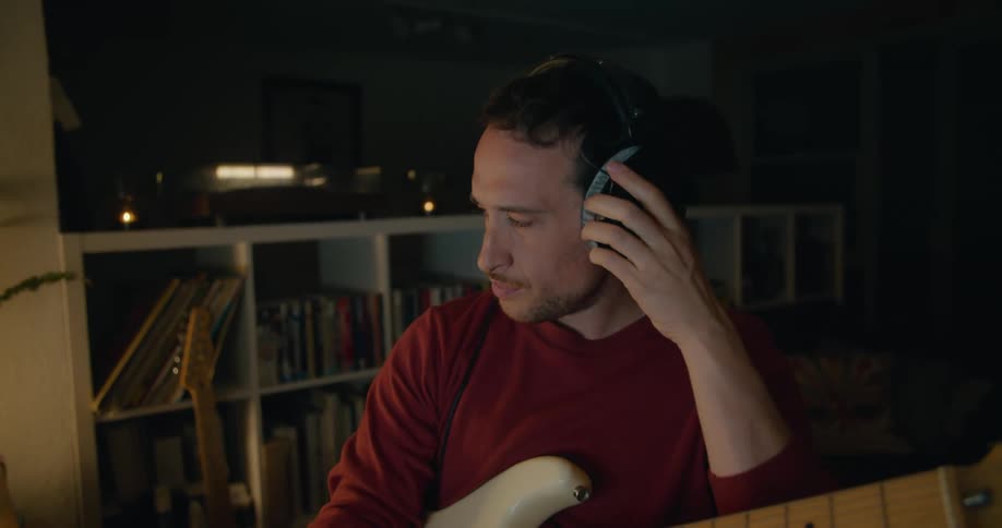 A man is playing guitar as he pauses and starts to think