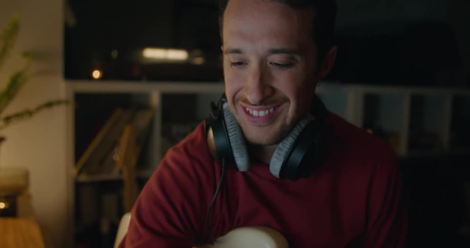 Man with headphones and bass guitar picks up smartphone and reads messages